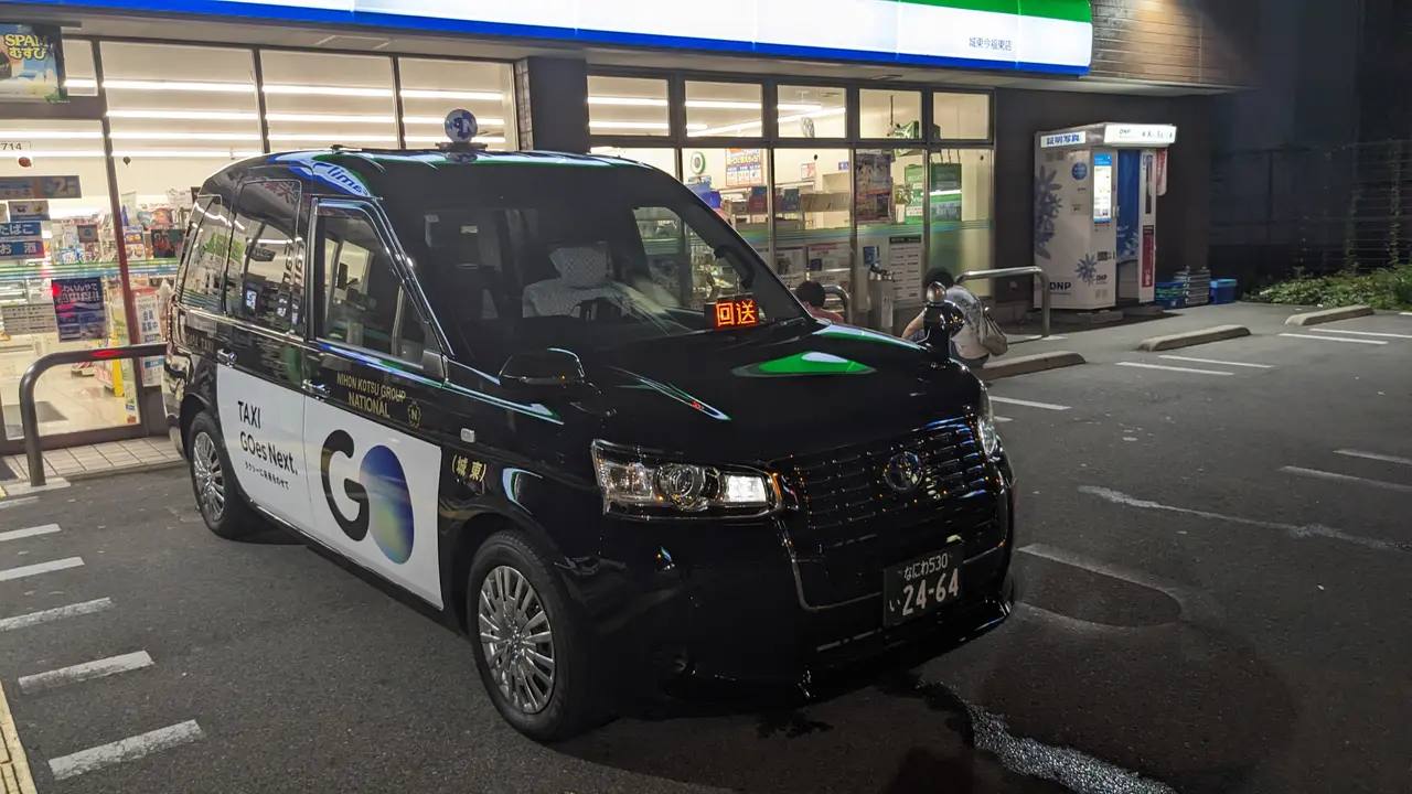 Ein „JPN Taxi“ von Toyota – das kastenförmige japanische Universal-Design-Taxi – an einer Straße in Tokio.