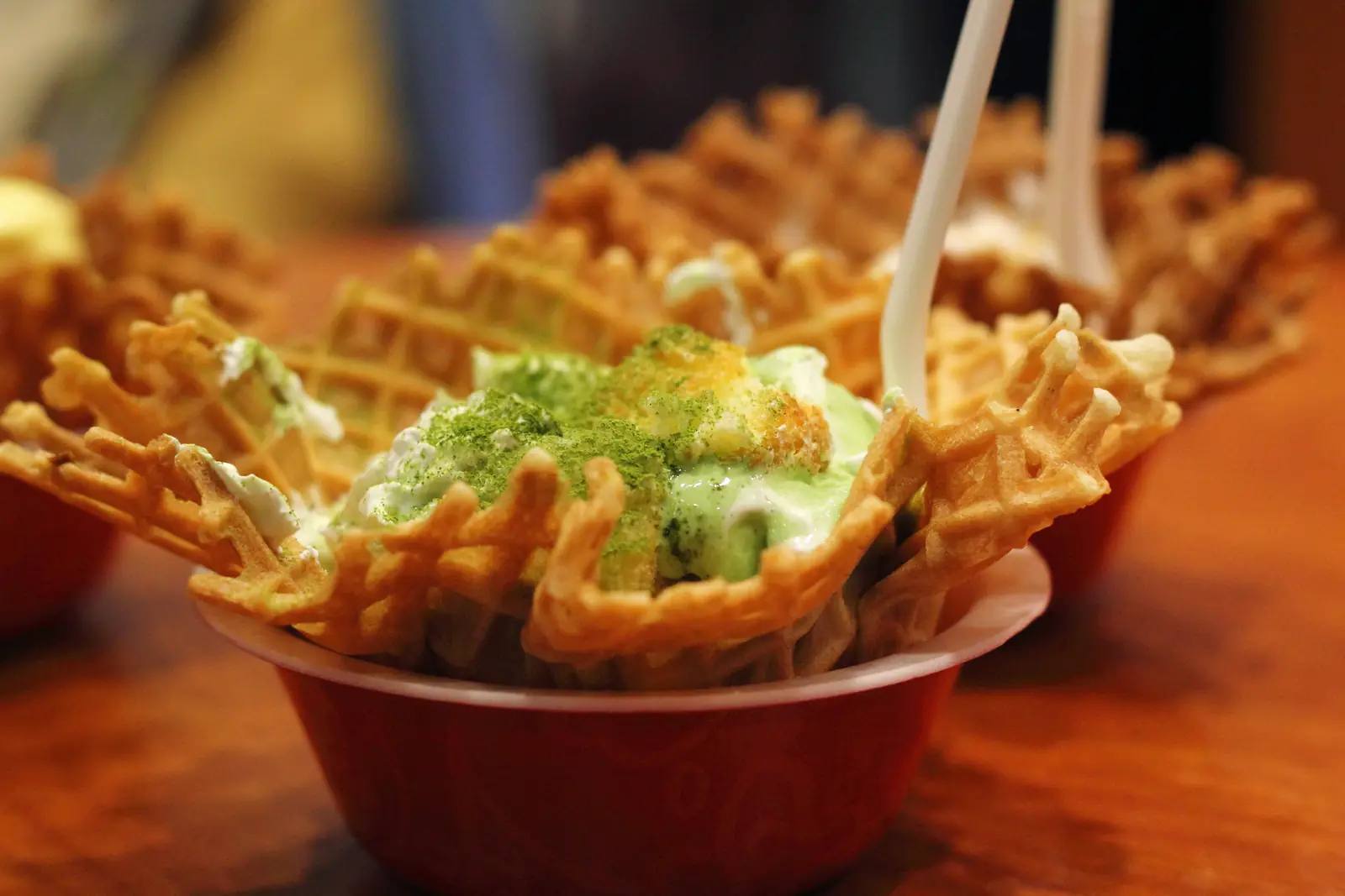 Grünes Matcha-Softeis in einer Waffelschale, bestäubt mit Matcha-Pulver