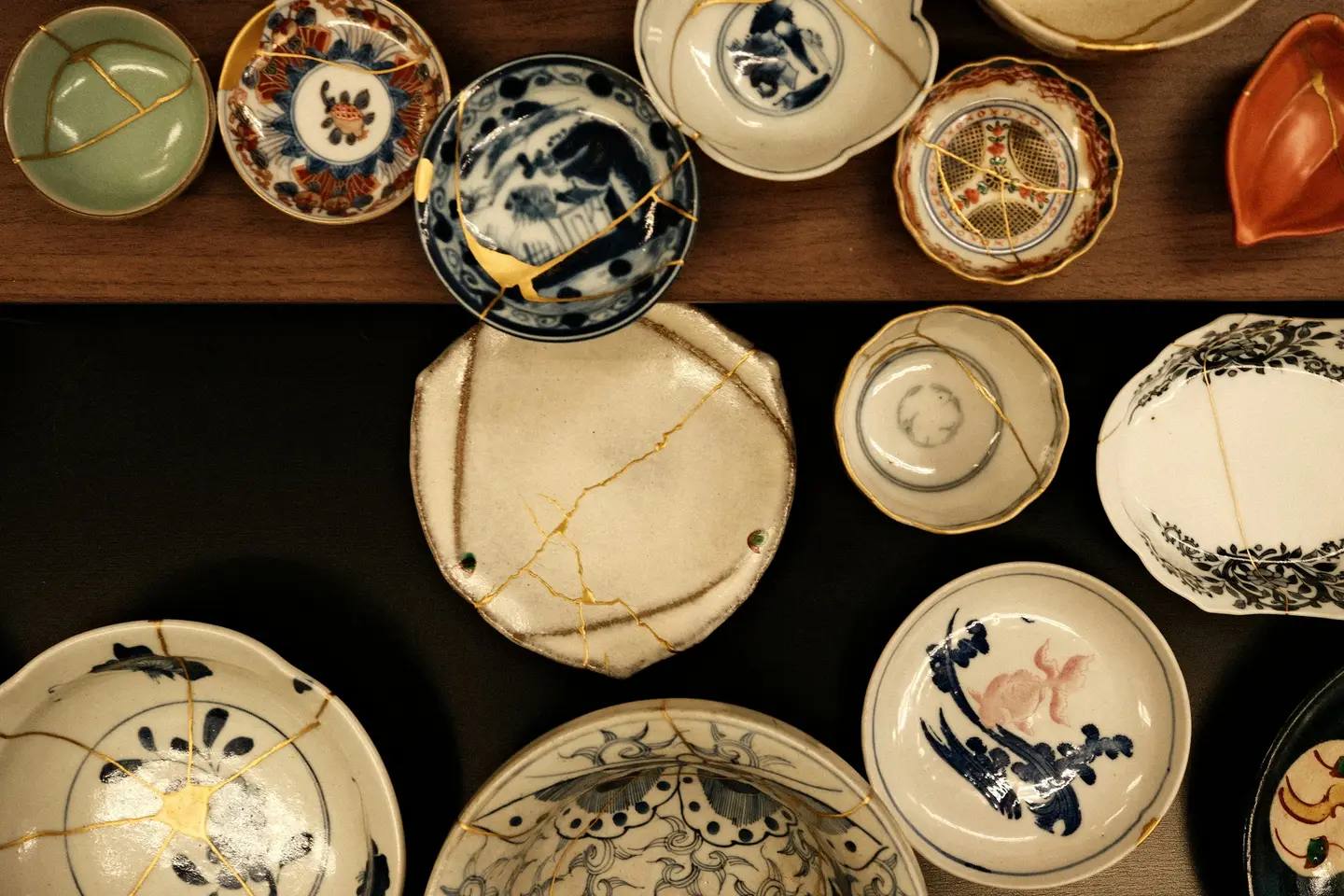 Numerous Japanese ceramic bowls and plates seen from above, their break lines joined with gold.
