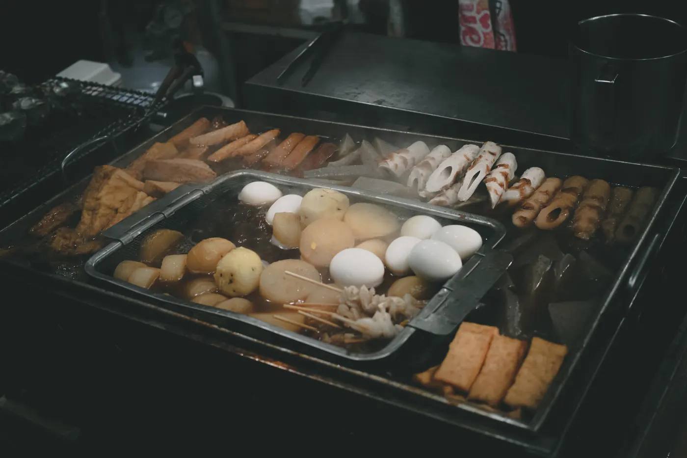 Dampfende Oden-Theke mit Eiern, Daikon-Rettich, Chikuwa-Fischküchlein und Tofu, die in heißer Dashi-Brühe köcheln